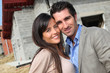 © goodluz - Happy couple standing in front of house under construction