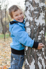 Wall Mural - Cheerful boy hugging birches, autumn park