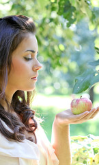 Cute young woman holding an apple in her hands against the backg