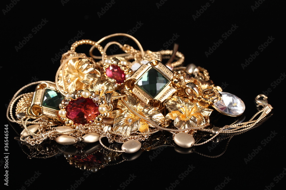 Various gold jewellery on black background