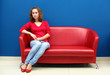 © Sergey Nivens - Young woman sitting on red sofa