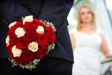 Groom holding wedding bouquet of red roses