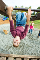 Wall Mural - Kid hanging upside down on school playground equipment