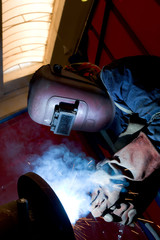 Wall Mural - factory worker welding metal and sparks spreading