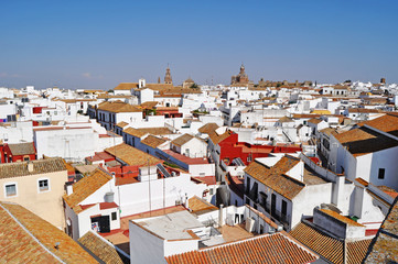 A picturesque view  of one  of the typical white towns in Andalusia Southern Spain with it’s dazzling assortment  of white houses and distinctive buildings in the background 