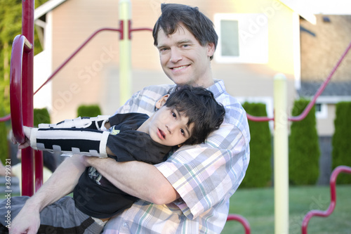 Fotografia, Obraz Father helping disabled son to play at playground