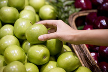 Female Hand Grabbing Green Apple In Market.