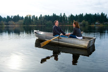 Happy Couple In Love Rowing A Small Boat On A Quiet Lake