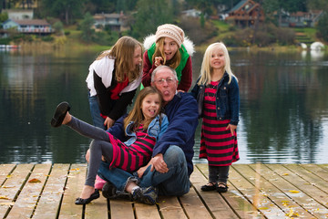 Wall Mural - A happy gray haired Grandpa with 4 Grandchildren on a lake