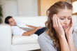 © WavebreakmediaMicro - Woman experiencing headache with man on the sofa behind her
