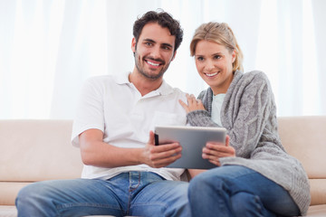 Poster - Smiling couple using a tablet computer