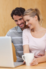 Poster - Portrait of a couple using a laptop while having tea