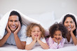 © WavebreakmediaMicro - Happy family hiding under the blanket
