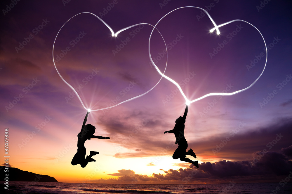 Foto-Kissen - young couple jumping and drawing connected hearts by flashlight