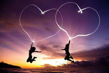 Young Couple Jumping And Drawing Connected Hearts By Flashlight