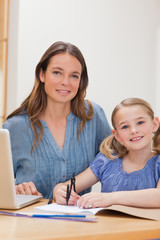 Wall Mural - Portrait of a beautiful woman helping her daughter doing her hom