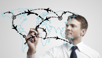 Young business man drawing an airplane routes on world map