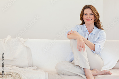 Smiling mature woman sitting on sofa Poster Mural XXL