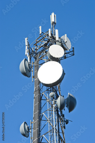 Fotografie, Tablou Cell tower and radio antenna in trees against a blue sky