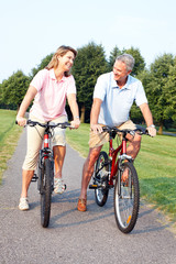 Poster - Senior couple cycling in park.