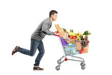 Young Man Running And Pushing A Shopping Cart Full With Food