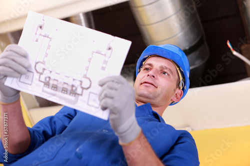 Fotografija Man looking at plans for a heating installation
