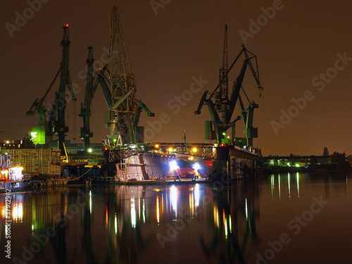 Fototapeta na wymiar Big cranes and dock at the shipyard at night.