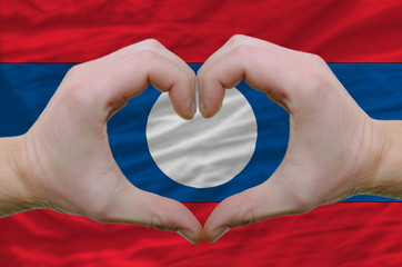 Heart and love gesture showed by hands over flag of laos backgro