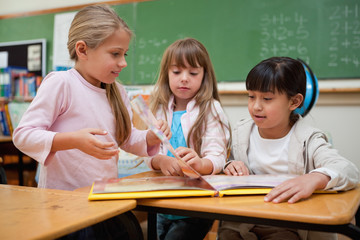 little schoolgirls reading a fairy tale to their classmate
