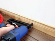 Male hand with carpenter tool installing baseboard