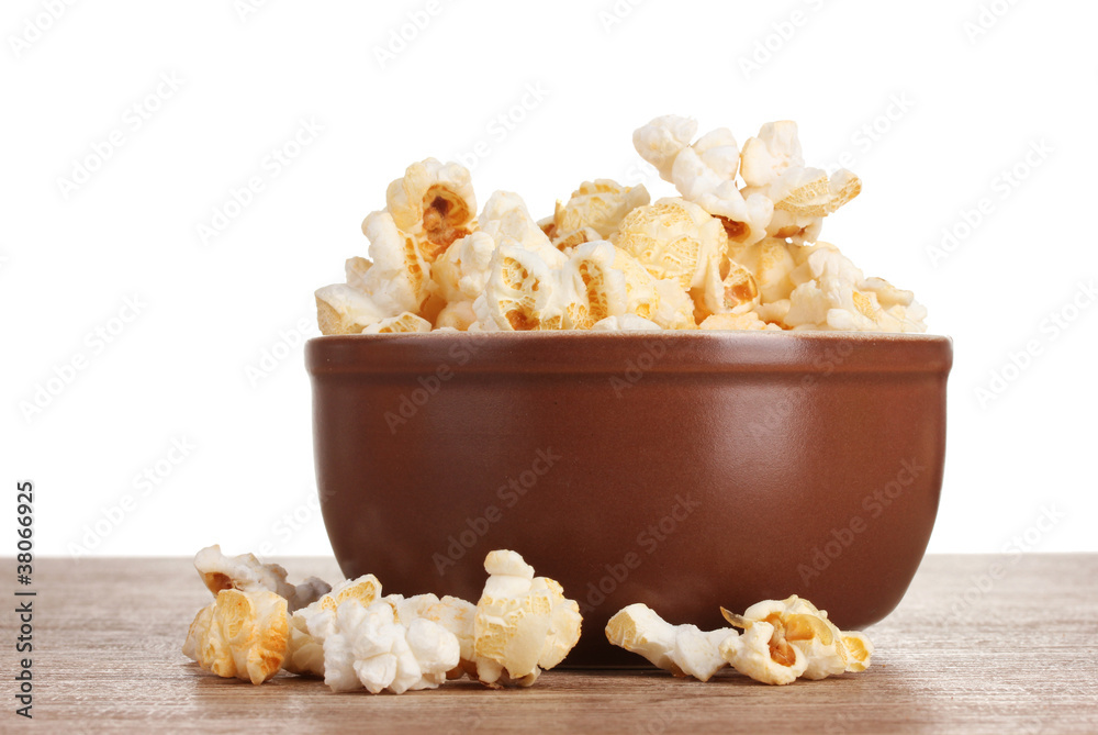 popcorn in brown bowl on wooden table on white background
