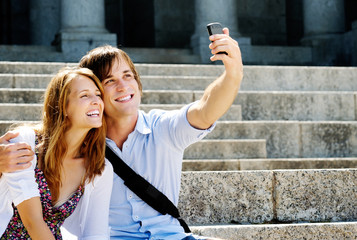 Wall Mural - happy couple uses a smartphone to take a picture