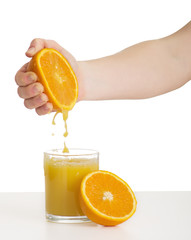 hand squeezes the juice from the orange into a glass