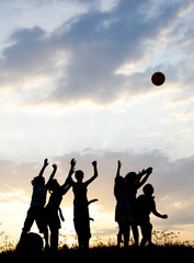 Wall Mural - Silhouette, group of happy children playing on meadow,