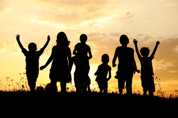 Wall Mural - Silhouette, group of happy children playing on meadow