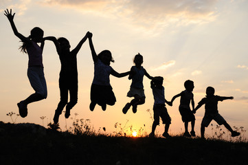silhouette, group of happy children playing on meadow,