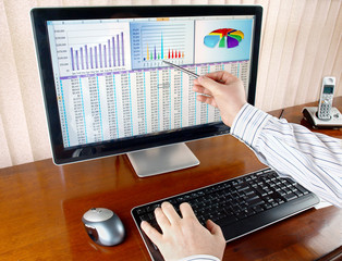 Fototapete - Analyzing  financial data and charts on computer screen.