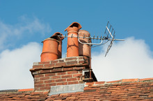 Clay Chimney Pots On Old Tiled Roof