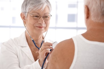 Wall Mural - Senior female doctor examining male patient