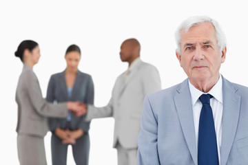 Poster - Mature businessman with trading partners behind him
