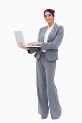 Poster - Smiling businesswoman using laptop while standing