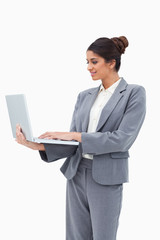 Poster - Smiling businesswoman using her laptop while standing