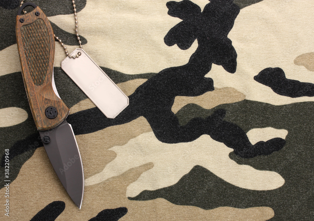 Army badges and knife on camouflage background