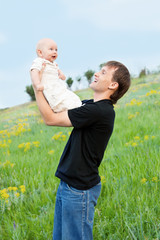 Wall Mural - happy young man playing his baby boy on nature on slope