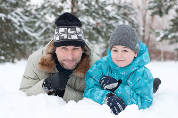 Canvas Print - Dad and son rest in the snow in the park