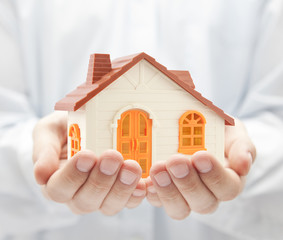 Canvas Print - Small orange toy house in hands