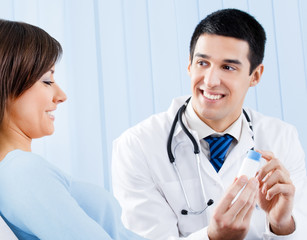 Smiling doctor with drug and patient at office