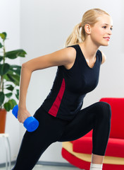 Woman exercising with dumbbell, at home