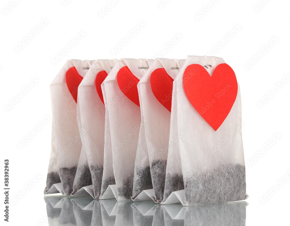 Tea bags with blank heart-shaped labels isolated on white