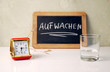 © Sinuswelle - Stilleben mit Wasserglas, Kreidetafel, Aufstehen und Wecker